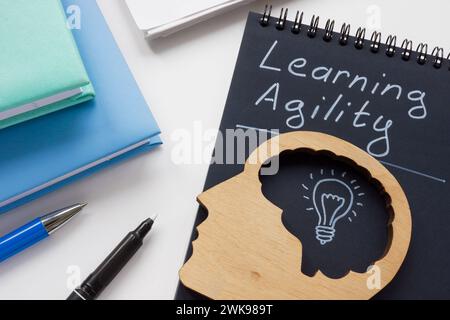 Notepad with inscription learning agility and head model. Stock Photo