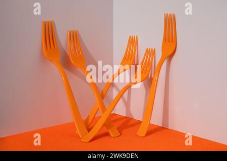 Five orange plastic forks on orange and white background Stock Photo