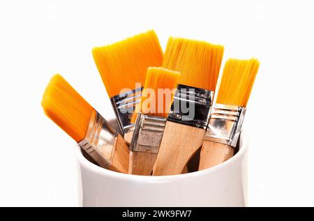 Orange synthetic brushes of different sizes in a vertical position. Stock Photo