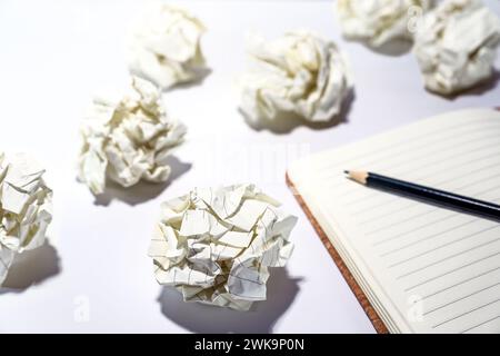 Discarded crumpled paper balls around an empty notebook with a pencil, concept for creative writing, development process, business frustration and str Stock Photo