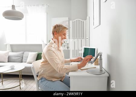 Mature female programmer working with tablet computer at home Stock Photo