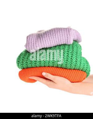 Female hands with stack of different stylish sweaters on white background Stock Photo