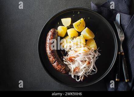 Bloody sausage morcilla, stewed sour turnip and mashed potato with brown beans close up. Traditional Slovenian dish with roasted bloody sausage Stock Photo