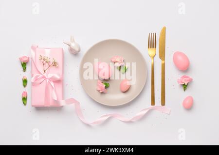 Cute Easter table setting with pink gifts, flowers and eggs on white background Stock Photo