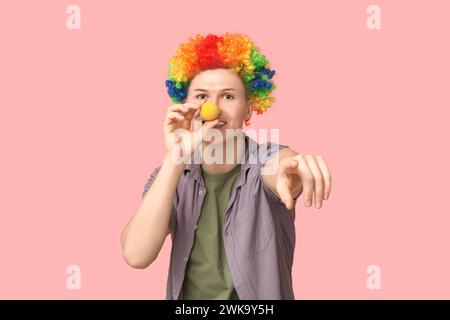 Handsome young man in funny disguise pointing at viewer on pink background. April fool's day celebration Stock Photo