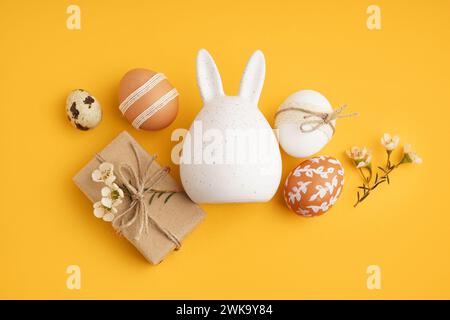 Decorated Easter eggs, bunny figure and present on yellow background Stock Photo