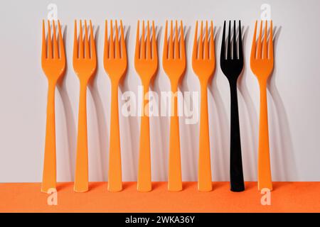Five orange plastic forks on orange and white background Stock Photo