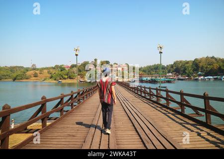 Traveler Walking on Mon Bridge Songkalia River, the Iconic Landmark of Sangkhlaburi District, Kanchanaburi, Thailand Stock Photo