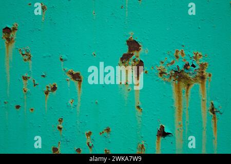 Peeling turquoise paint and rust stains on metal surface. Stock Photo