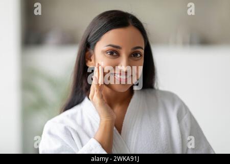 Pretty indian woman in white bathrobe posing at white bathroom Stock Photo