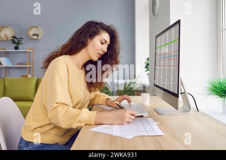 Female analyst checking spreadsheet on computer and doing paperwork Stock Photo