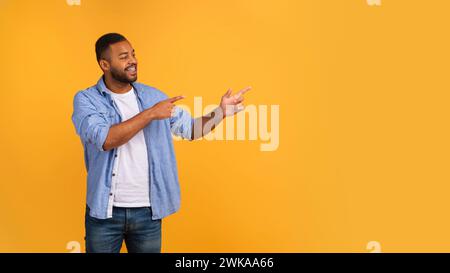 Energetic young black man pointing at copy space with two hands Stock Photo