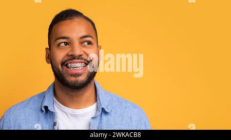 Smiling young african american man with orthodontic braces looking at copy space Stock Photo