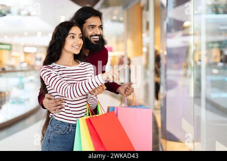 Loving young eastern couple standing in shopping mall with purchases Stock Photo