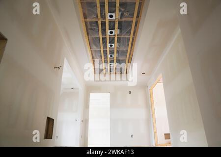 Unfinished hallway with opening in plasterboard ceiling for installation of recessed spotlights in upscale two storey home. Stock Photo
