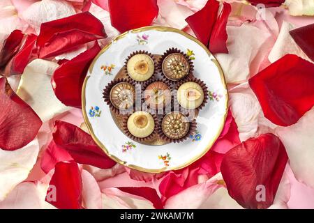 Artisan chocolates arranged on vintage plate amidst rose petals Stock Photo