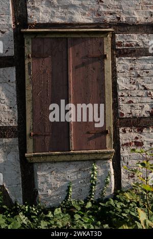 Details of a half-timbered house  in need of renovation , the shutter is closed, the fittings are rusted, white stone wall, the paint is peeling off, Stock Photo