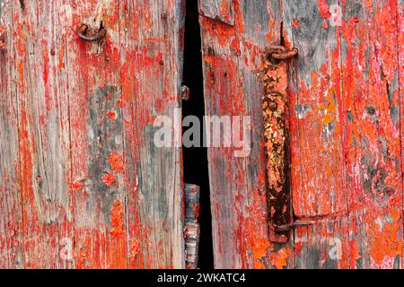 Peeling red paint on the door of an abandoned barn. Stock Photo