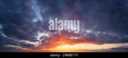 Overcast sky at sunset. The sun is setting on the horizon, gray pre-rain clouds. Stock Photo
