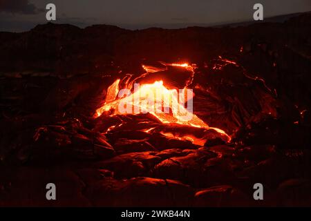 Active lava flow on Hawaii, magma is coming out of a crevice, slowly cooling down and solidifying in various patterns, glow of the lava Stock Photo