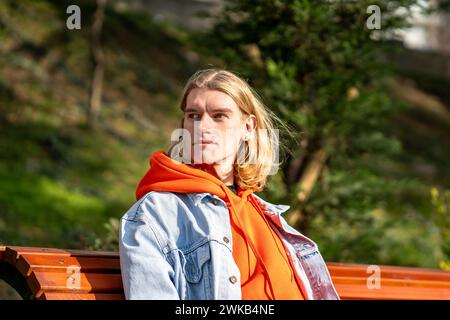Stylish guy sitting on bench, waiting for beloved girlfriend, having romantic date in sunny day Stock Photo