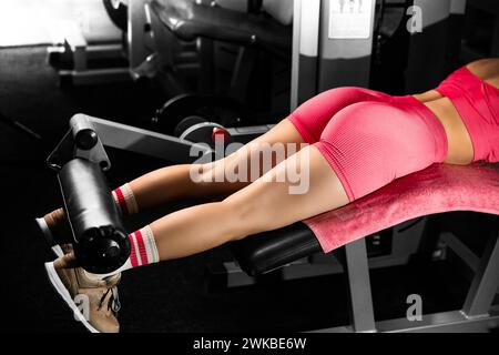 Close up view gym seated leg curl machine exercise woman at indoor in gym. Health concept. Stock Photo