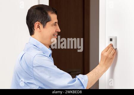 Shot of a side view portrait of a beautiful happy business man push button digital thermostat at house Stock Photo