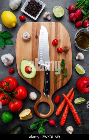 Overhead dark tabletop image of real colorful healthy nutritious raw vegetable and fruit plant-based vegetarian and vegan diet foods placed on a wood Stock Photo