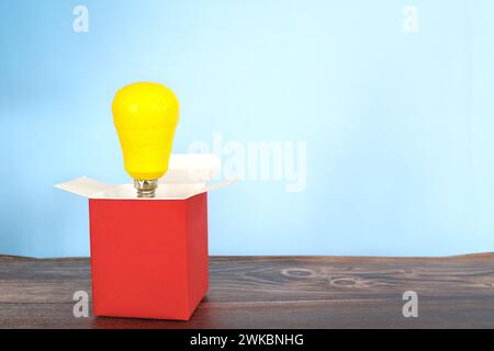 Yellow light bulb coming out of a box. Think outside the box concept. Stock Photo