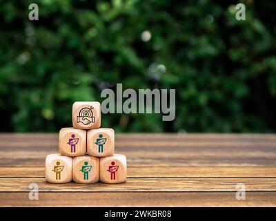 Cooperation icon on top of wood cubes pyramid shape with human holding leaf symbols. Green life society community members sustainability, conserve res Stock Photo