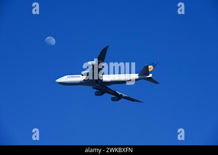 Chantilly, Virginia, USA - February 19, 2024: A Lufthansa Boeing 747-830 passenger airplane flies past the moon as it approaches Dulles Airport. Stock Photo