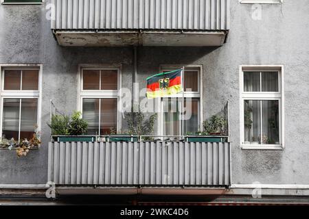 A German flag with a federal eagle flutters on the balcony of a run-down apartment building, Berlin, 11 October 2019 Stock Photo