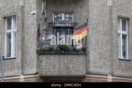 A German flag with a federal eagle flutters on the balcony of a run-down apartment building, Berlin, 22/01/2020 Stock Photo