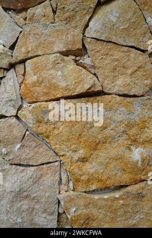 An ancient weathered stone wall with numerous cracks and chips Stock Photo