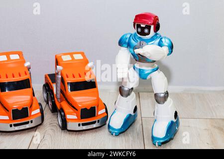 on the floor there are children's toy cars made of plastic and a robot. Stock Photo