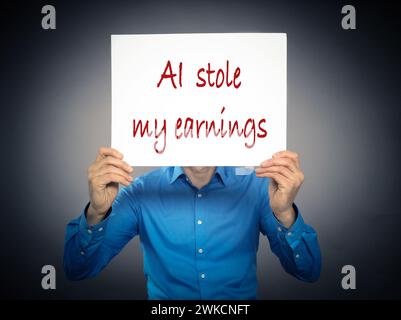 Business man holding a white sign with the text AI stole my earnings in front of his face Stock Photo
