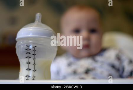 File photo dated 20/11/23 of a baby in a high chair looking towards her bottle of milk in the foreground. A new probe into the supply of baby formula milk has been launched by Britain's competition watchdog after it found that average prices had soared by 25% in the past two years. The Competition and Markets Authority (CMA) said it has begun a market study into formula supply following findings last November of an initial review into the sector. Issue date: Tuesday February 20, 2024. Stock Photo