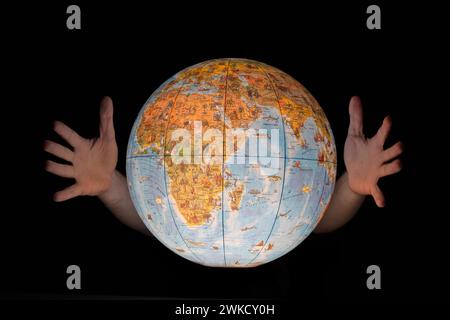 Male hands engulfing a glowing earth globe, isolated on black Stock Photo