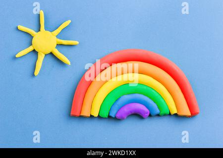 Plasticine rainbow and sun on color blue background Stock Photo