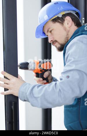 workman using cordless drill on door Stock Photo