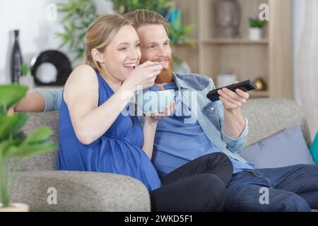 couple watching movie with popcorn in living room Stock Photo