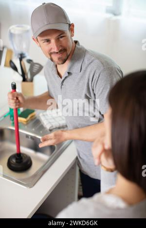 cleaning clogged pipes in the kitchen sink with a plunger Stock Photo