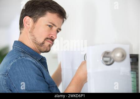 man fixing curtain on to rail Stock Photo