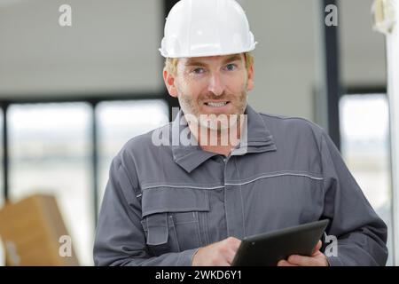 portrait of mature male worker wearing overalls holding digital tablet Stock Photo