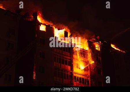 Pieces of the house fall due to the fire. Fire blazing in apartment building. Stock Photo