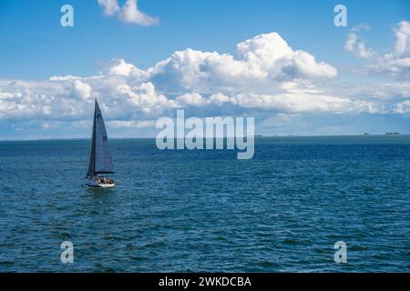Eine Segelyacht in der Nordsee im Wattemeer an der Nordseeküste Windkraftanlagen und Inseln im Hintergrund Stock Photo
