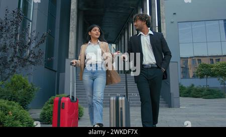 Two formal people walking at city outdoors outside airport arriving business trip talking together walk with luggage baggage talk cooperation Stock Photo