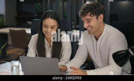 Cheerful Caucasian colleagues business partners people male man businessman leader manager and female businesswoman woman sitting at desk with laptop Stock Photo