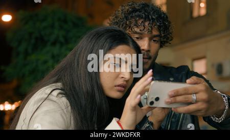Indian Arabian couple lost in new evening city love guy girl woman man friends boyfriend girlfriend night urban tourism travel searching way looking Stock Photo