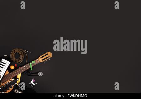 Musician's workspace with various instruments and recording accessories on a dark surface - Creative process and music arrangement concept - flat lay Stock Photo